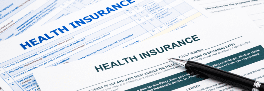 A pile of health insurance program options. There ia a pen laying on top of the pile.