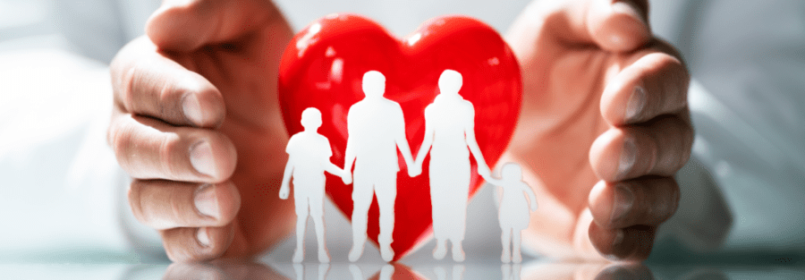 White cutouts of a family in front of a heart sculpture.