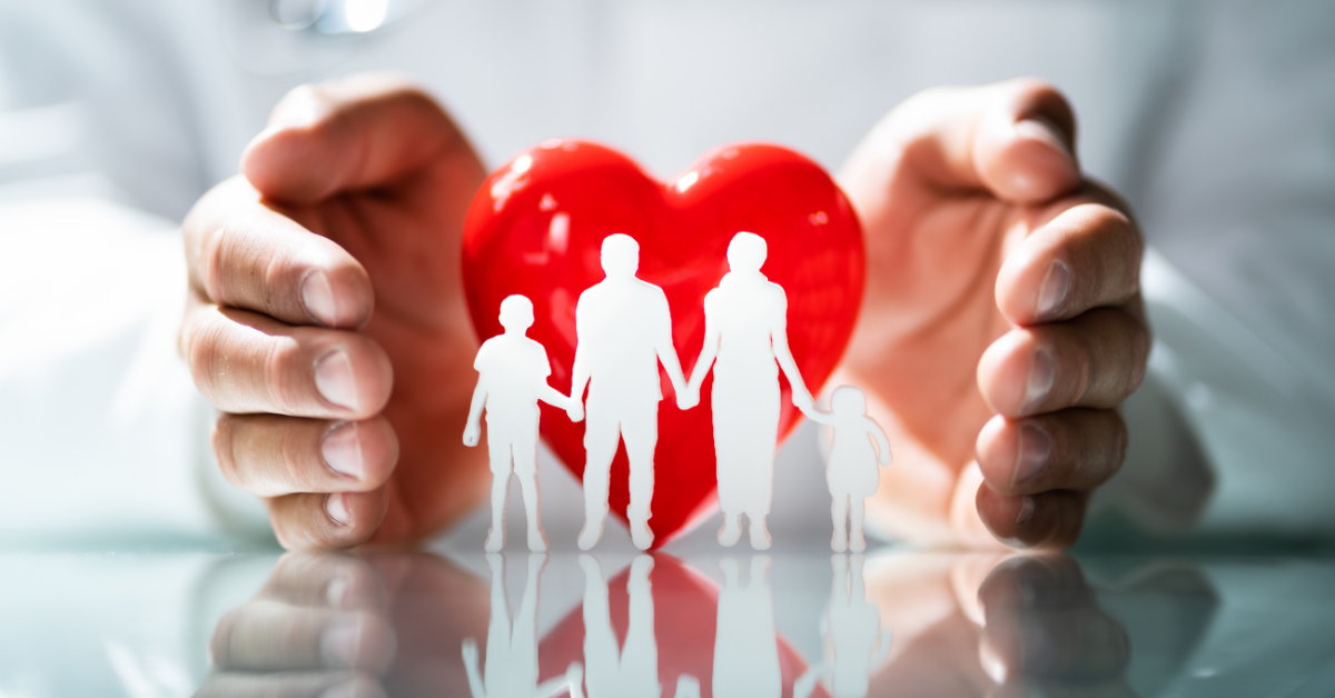 White cutouts of a family in front of a heart sculpture.