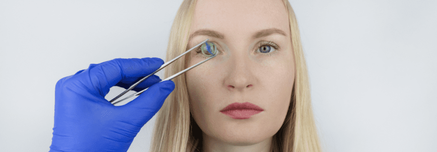 A woman with a doctor holding a glass in front of her right eye.