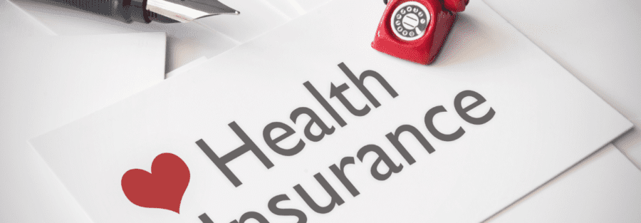 A paper that says "health Insurance" with a red telephone off to a corner.