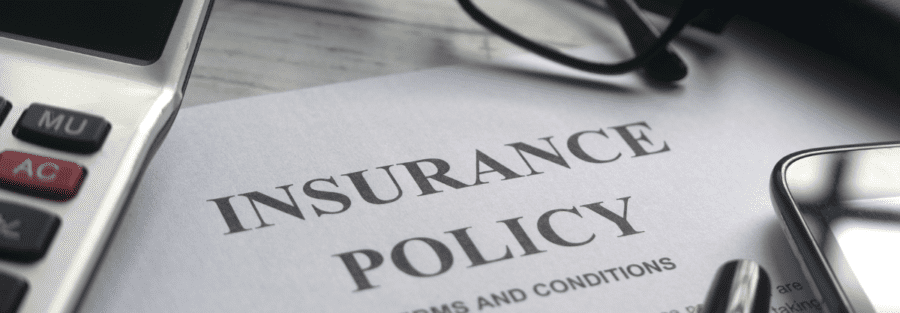 A health insurance plan with a pair of glasses, calculator, and pen on top of the papers.