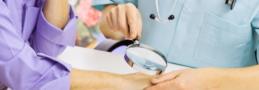 A dermatologist with a magnifying glass on a woman's hand.
