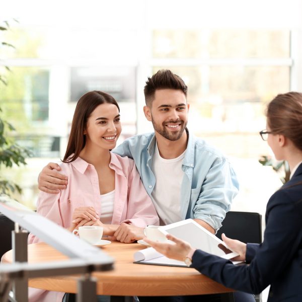 Female insurance agent working with young couple in office